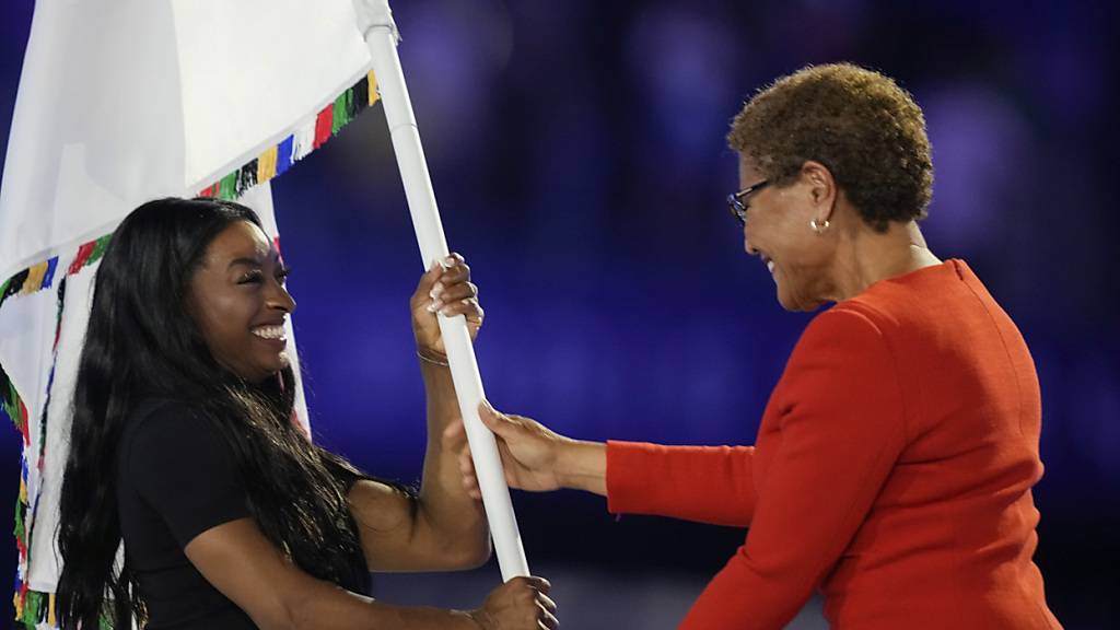 Karen Bass, Bürgermeisterin von Los Angeles, nimmt die Olympische Flagge von Kunstturnerin Simone Biles entgegen