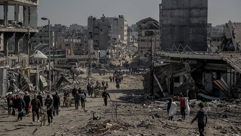 Palästinenser gehen nach dem Rückzug der israelischen Armee aus dem Norden des Gazastreifens neben beschädigten Gebäuden zurück in ihre Häuser. 