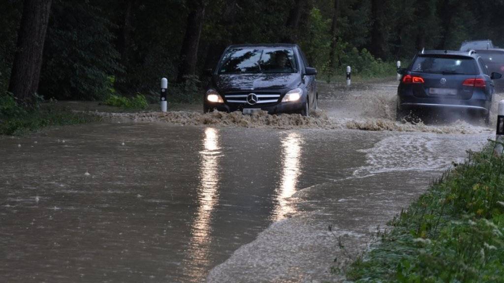 Der Dauerregen hat dem Verkehr in der Ostschweiz zugesetzt: Autofahrer unterwegs auf einer überschwemmten Strasse zwischen Diepoldsau und Berneck.