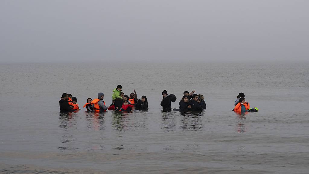 ARCHIV - Eine Gruppe kurdischer Migranten aus dem Iran und dem Irak weigert sich am Strand von Ambleteuse in Nordfrankreich an Land zurückzukehren. Foto: Bernat Armangue/AP/dpa/Archivbild