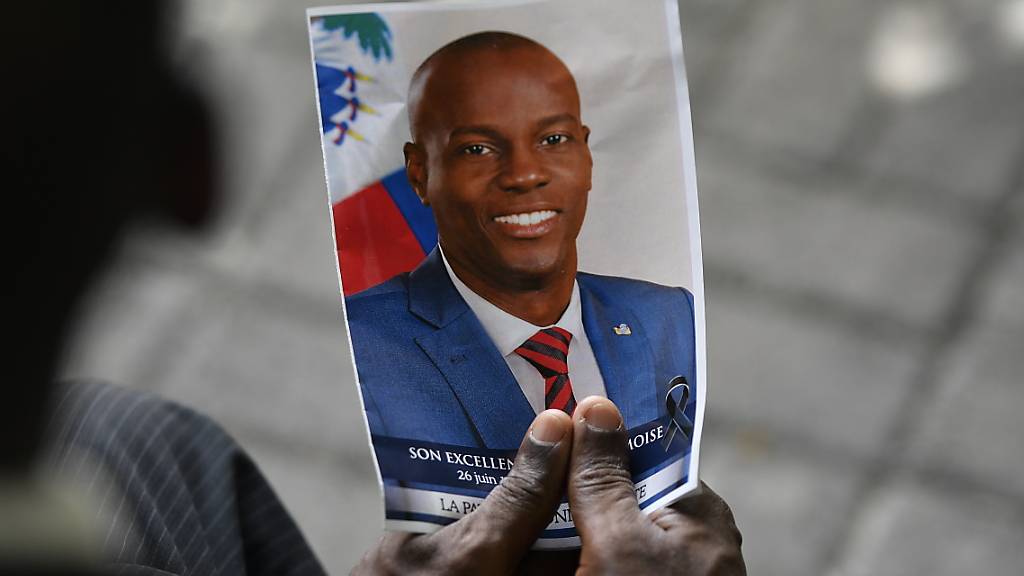 ARCHIV - Eine Person hält ein Foto des verstorbenen haitianischen Präsidenten Jovenel Moise während einer Gedenkfeier im Nationalen Pantheon Museum. Gut ein halbes Jahr nach der Ermordung ist ein zweiter Tatverdächtiger in den USA festgenommen und am Donnerstag in Miami zum ersten Mal verhört worden. Foto: Matias Delacroix/AP/dpa