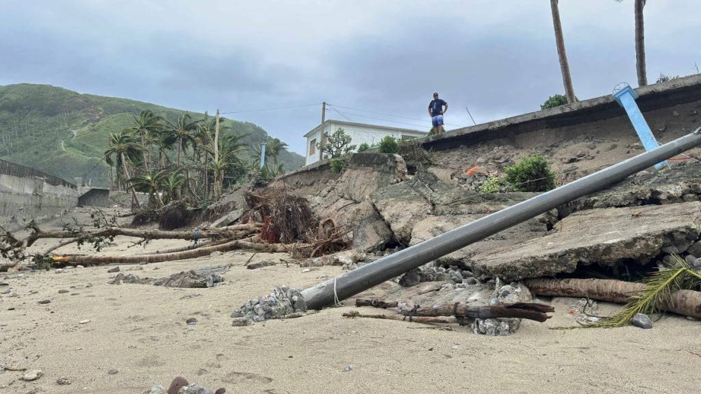 Ein Mann steht neben einer durch den Taifun Ragasa beschädigten Straße in der Provinz Batanes. Foto: Justine Mark Pillie Fajardo/AP/dpa