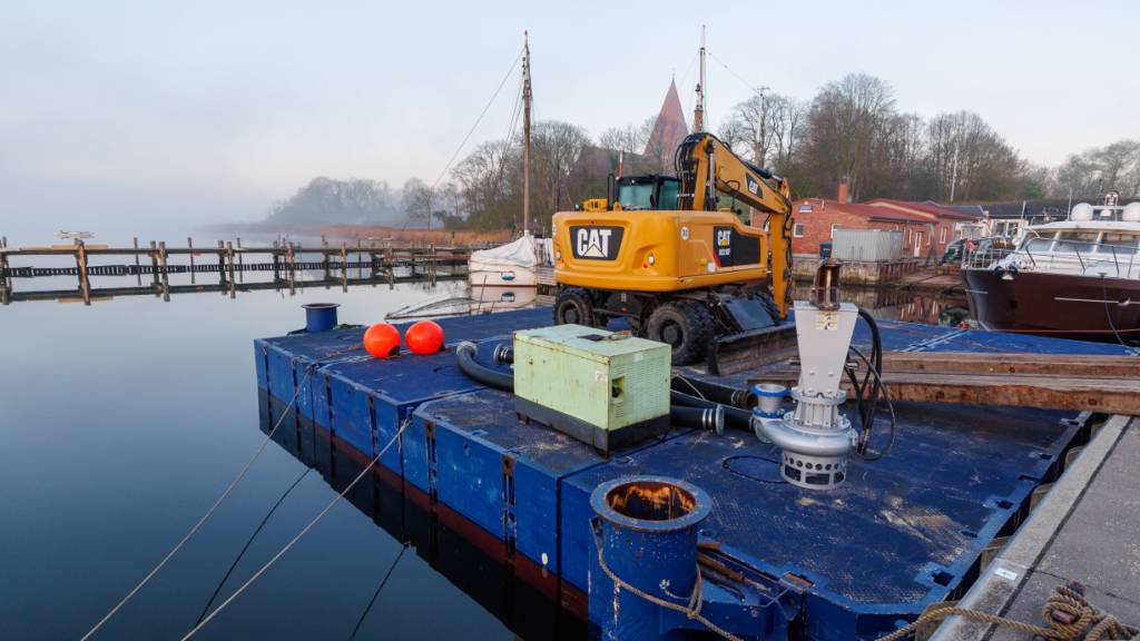 Ein Bagger steht am Morgen auf einem Ponton und soll später bei der Rettung des Buckelwals vor der Ostseeinsel Poel eingesetzt werden. Für den vor der Insel Poel gestrandeten Buckelwal hat ein neuer Rettungsversuch begonnen. Umgesetzt wird das Konzept von einer privaten Initiative. Foto: Jens Büttner/dpa