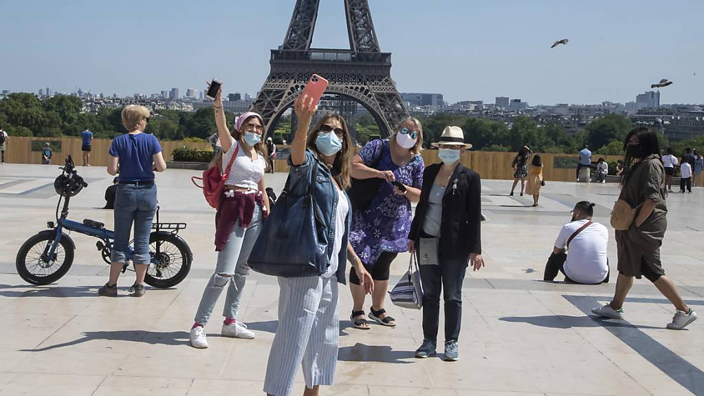 Menschen mit Mundschutzen machen Selfies vor dem Eiffelturm auf dem Trocadero-Platz. Die Pariser genießen ihr erstes Wochenende in der Sonne seit den teilweisen Lockerungen der Reise- und Bewegungsbeschränkungen. Foto: Michel Euler/AP/dpa
