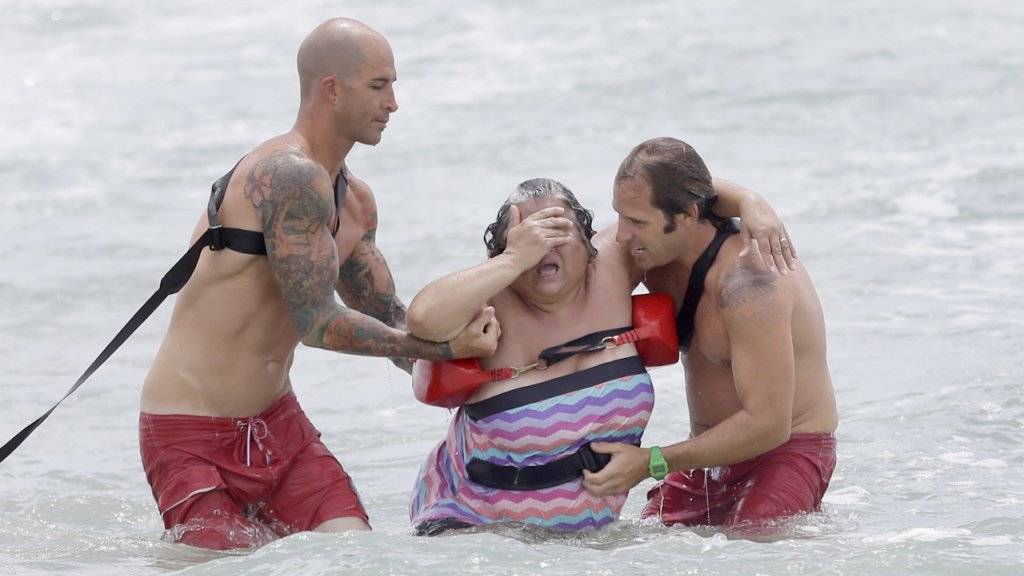 Rettungsschwimmer helfen einer Touristin in Florida aus dem Wasser: Eine ärztliche Behandlung in den USA kann unter Umständen teuer werden. (Symbolbild)