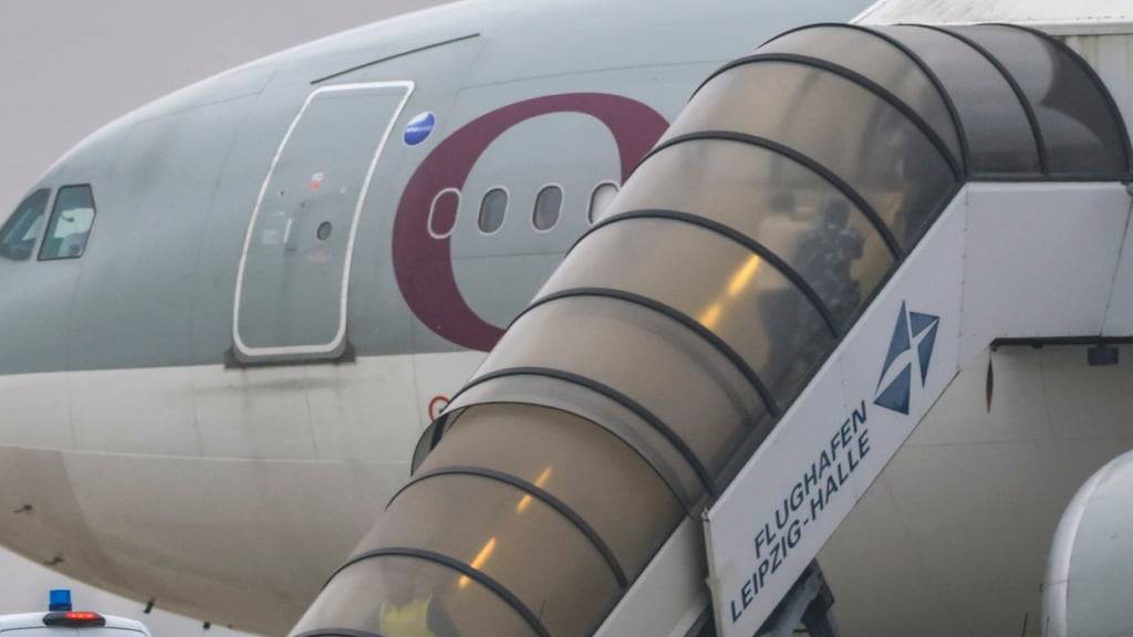 dpatopbilder - Menschen besteigen ein Flugzeug der Qatar Airways, vor dem Fahrzeuge der Bundespolizei stehen, auf dem Vorfeld am Flughafen Leipzig/Halle. Foto: Jan Woitas/dpa
