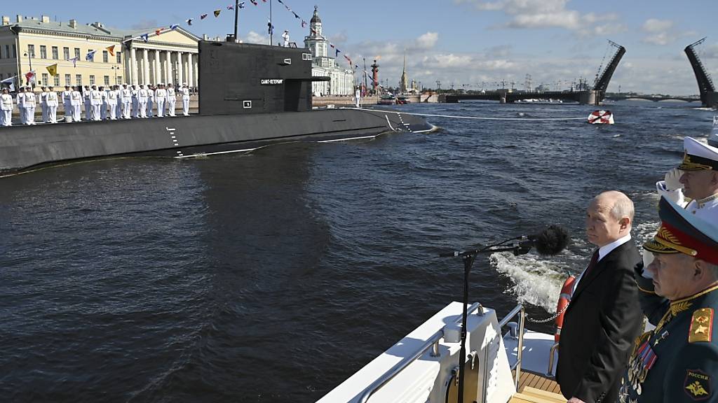 Wladimir Putin (l.) und sein Verteidigungsminister Sergej Schoigu (r.) sowie Admiral Nikolai Jewmenow (hinten) während der großen Marineparade zum Tag der Marine in St. Petersburg. Foto: Alexander Kazakov/Sputnik Kremlin/AP/dpa