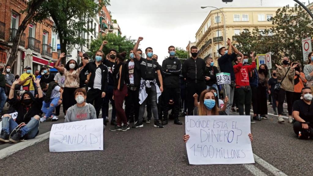 Demonstranten sitzen auf einer Strasse im Stadtbezirk Villa de Vallecas. Tausende Menschen haben in Madrid gegen die Abriegelungen von mehreren einkommensschwachen Gebieten der spanischen Hauptstadt zur Eindämmung der Corona-Pandemie protestiert. Foto: David Obach/EUROPA PRESS/dpa