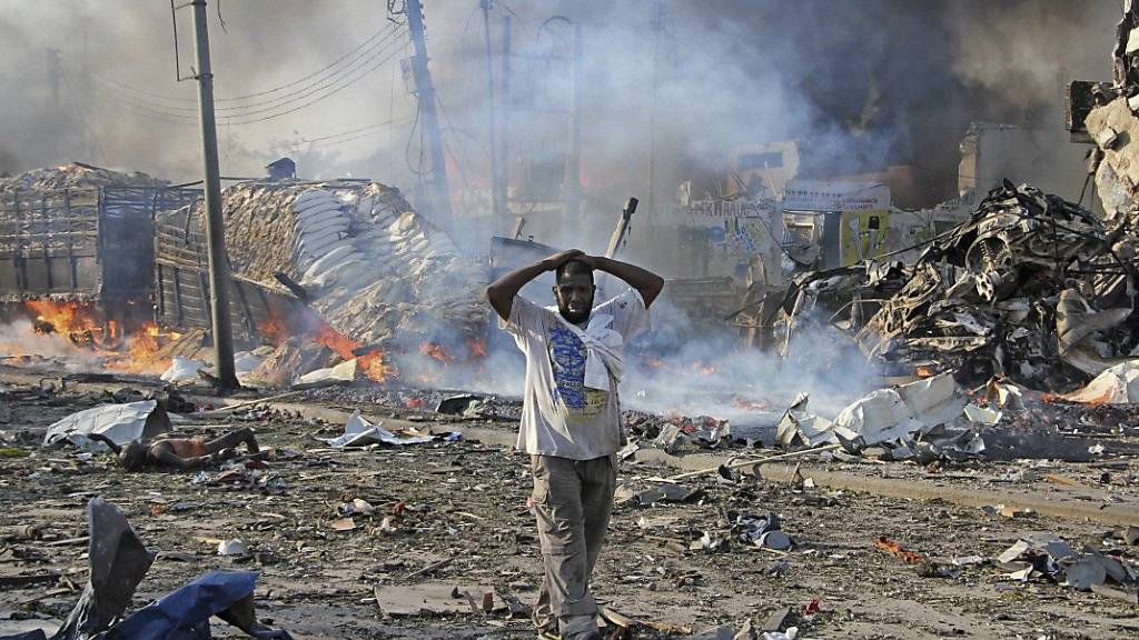 Ein Bewohner Mogadischus läuft traumatisiert an Leichen und Trümmern vorbei: Die Lastwagenexplosion war gewaltig und beschädigte auch die umliegenden Gebäude schwer.