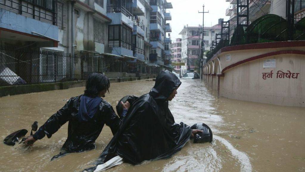 Nepalesen waten mit ihrem Motorrad durch die überfluteten Strassen der Hauptstadt Kathmandu.