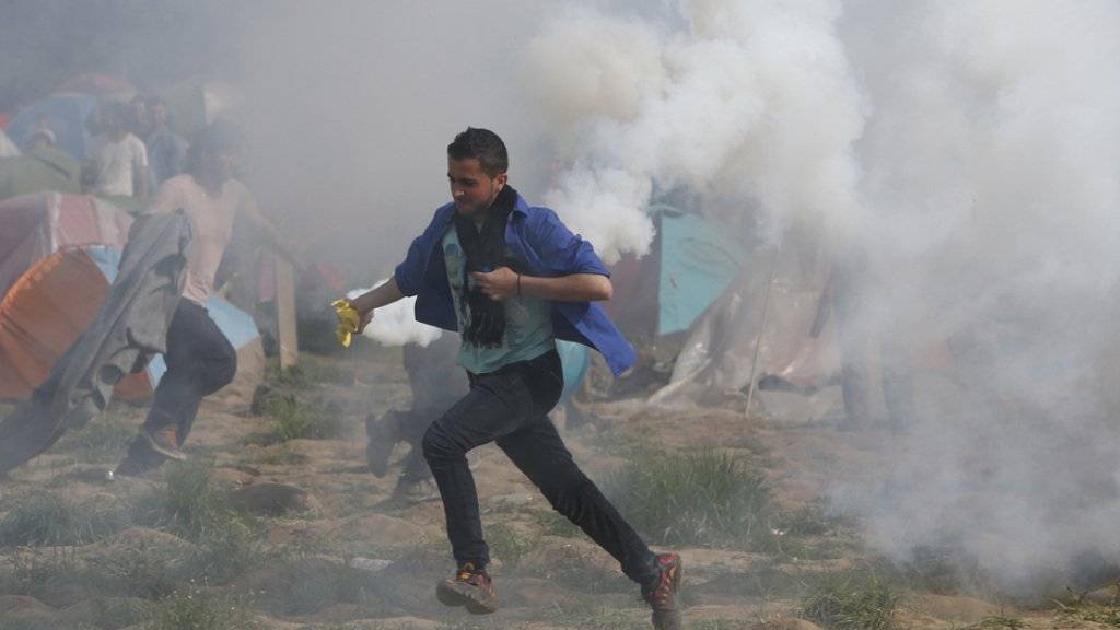 Ein Flüchtling in Idomeni flieht vor dem Tränengaseinsatz der mazedonischen Polizei.