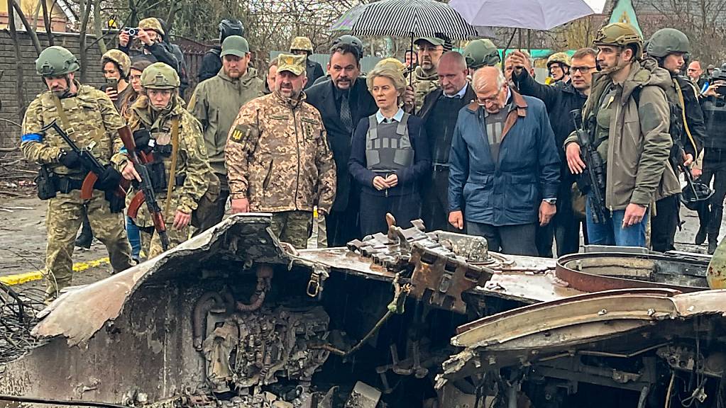 EU-Kommissionspräsidentin Ursula von der Leyen (M), der EU-Außenbeauftragte Josep Borrell (M,r) und Denys Schmyhal (hinter von der Leyen), Premierminister der Ukraine, stehen hinter zerstörten Militärfahrzeugen.