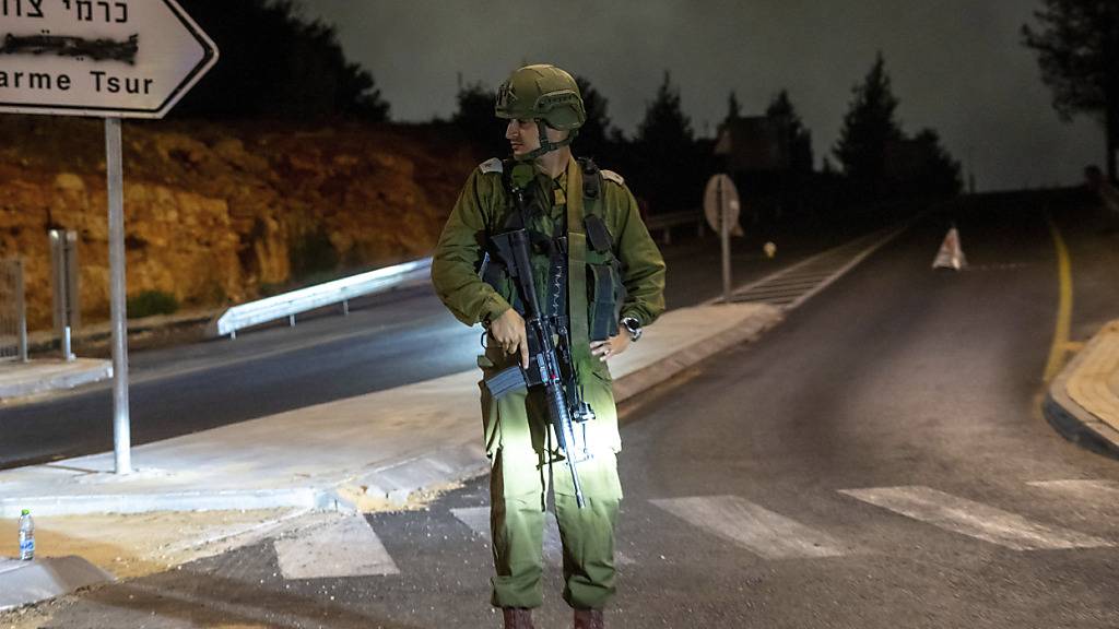 Ein israelischer Soldat steht in der Nähe des Tatorts einer Autoexplosion in der Siedlung Karmei Tzur im Westjordanland Wache. Foto: Ohad Zwigenberg/AP/dpa