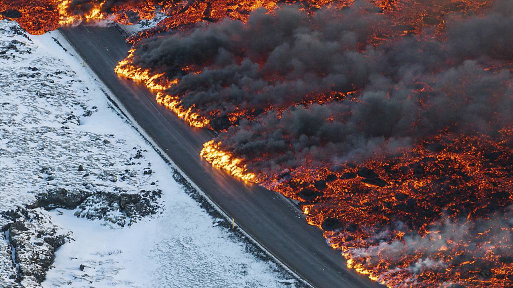 Lava fließt über die Hauptstraße nach Grindavik. Foto: Marco Di Marco/AP/dpa