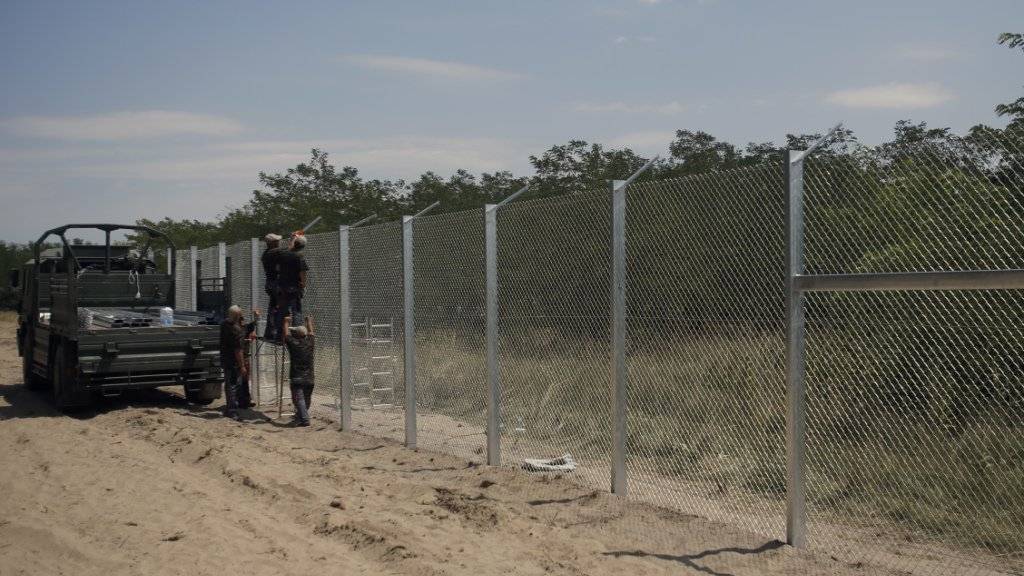 Ungarische Soldaten bauen einen Zaun zum Grenzschutz: Die Regierung will zudem Flüchtlinge aus bewohnten Gebieten verbannen.