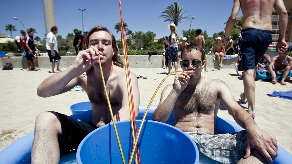 Zwei Männer trinken aus einem Bucket in Mallorca