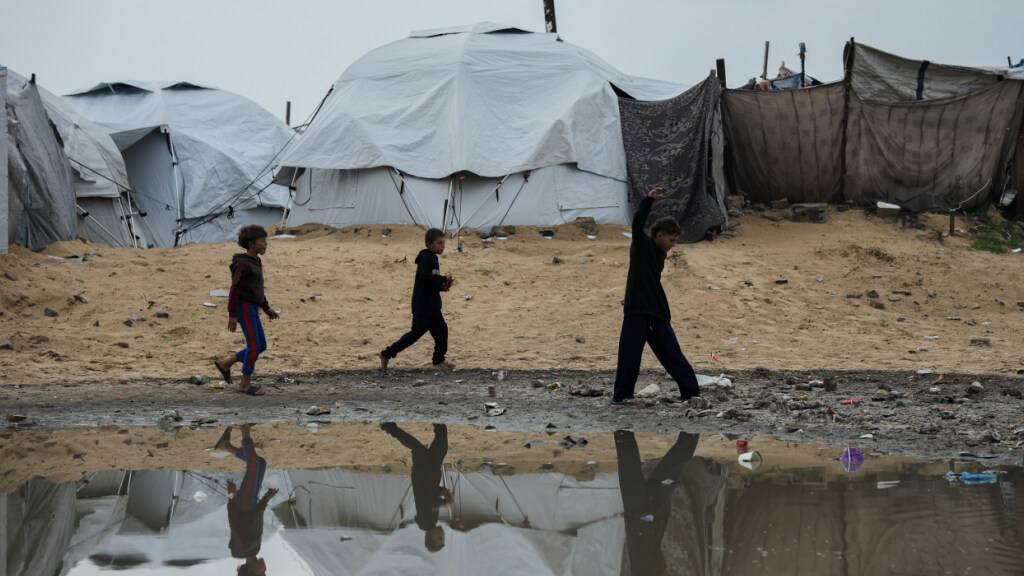 Vertriebene palästinensische Kinder laufen nach einem Unwetter durch ein Zeltlager in Gaza-Stadt. Foto: Jehad Alshrafi/AP/dpa