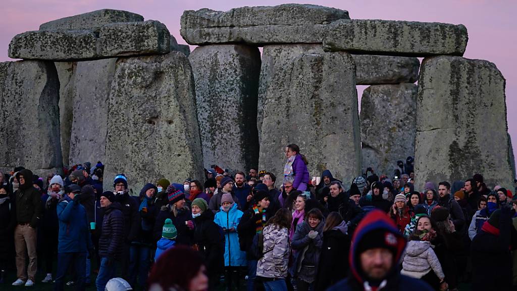 Einige Menschen sind am prähistorischen Monument von Stonehenge auf der Salisbury Plain versammelt, um an den Feierlichkeiten zur Wintersonnenwende teilzunehmen.