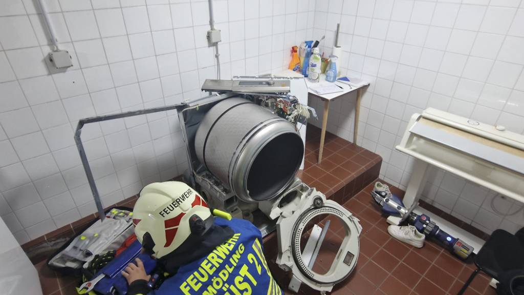 HANDOUT - Ein Mitarbeiter der Feuerwehr Mödling arbeitet in einem Raum, in dem eine 13-Jährige in einen Wäschetrockner geklettert war und sich nicht mehr selbst aus dem Gerät befreien konnte. Foto: Unbekannt/FFMOEDLING.AT/APA/dpa - ACHTUNG: Nur zur redaktionellen Verwendung im Zusammenhang mit der aktuellen Berichterstattung und nur mit vollständiger Nennung des vorstehenden Credits