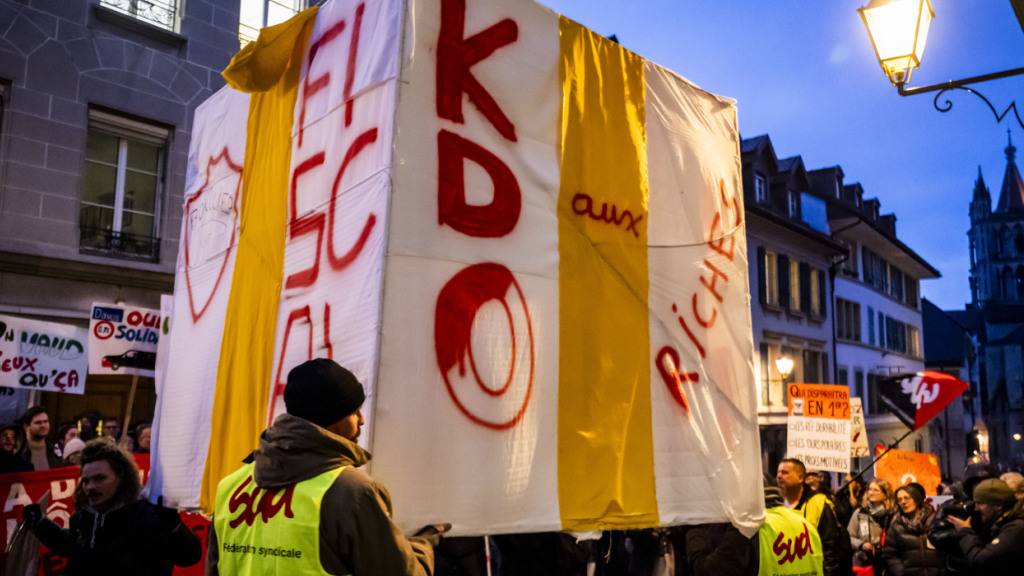 Vor dem Eingang des Grossen Rates des Kantons Waadt hatten die Gewerkschaften einen riesigen weissen Würfel aus Karton mit Geschenkumhüllung aufgestellt, der das Steuergeschenk des Steuerschildes für sehr reiche Menschen symbolisieren sollte.