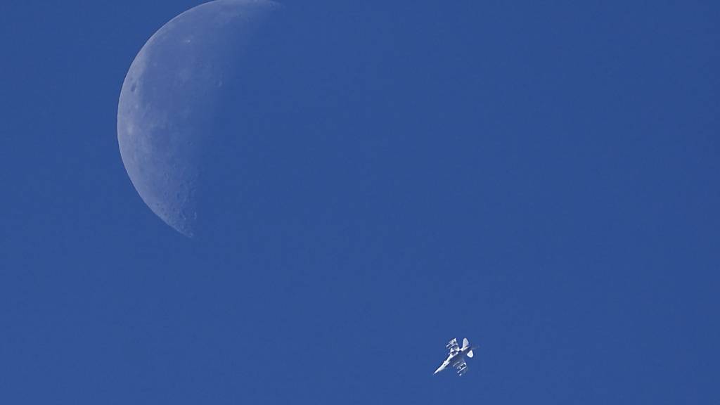 Ein israelischer Kampfjet überfliegt vor der Kulisse des Mondes den Gazastreifen. Foto: Ariel Schalit/AP/dpa