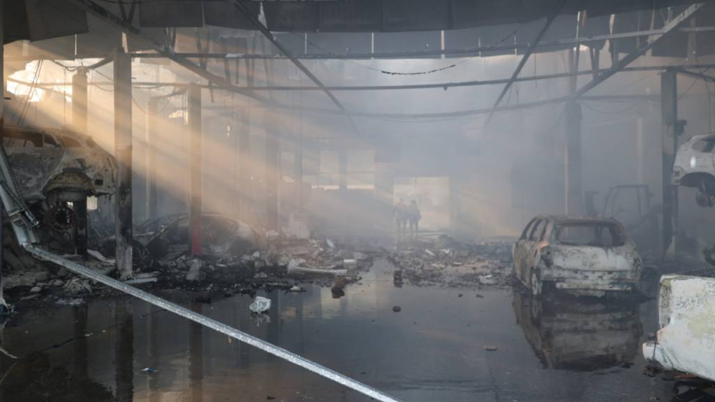 dpatopbilder - HANDOUT - Polizisten gehen durch eine Autowerkstatt in Saporischschja, die durch einen russischen Angriff zerstört wurde. Foto: Ukraine National Police/AP/dpa - ACHTUNG: Nur zur redaktionellen Verwendung und nur mit vollständiger Nennung des vorstehenden Credits