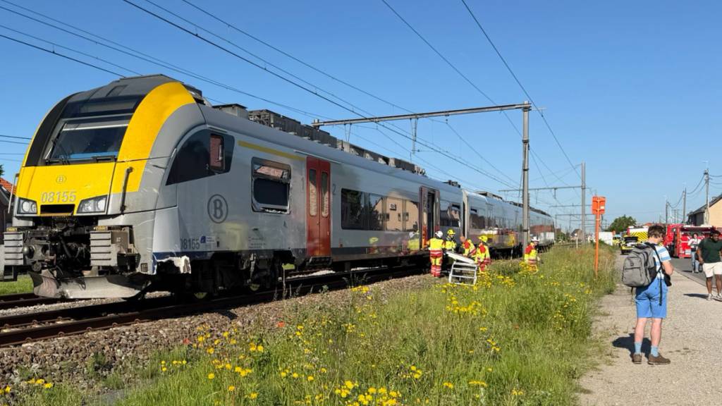 Rettungskräfte sind bei einem Unfallort im Einsatz, nachdem ein Zug mit einem Schulbus am Bahnübergang Vierhuizen in Buggenhout zusammengestoßen war. Foto: Koen Baten/AP/dpa