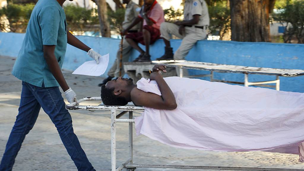 Ein medizinischer Mitarbeiter schiebt eine Trage auf der ein verwundetem Mann liegt, der bei einem Angriff auf das Afrik-Hotel verwundet wurde. Foto: Farah Abdi Warsameh/AP/dpa