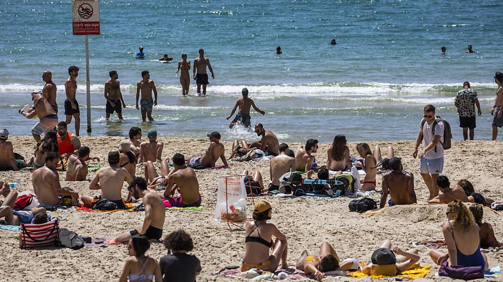 Menschen verbringen den Tag in der Sonne am Strand in Tel Aviv. Durch die fortgeschrittene Impfkampagne in Israel werden die Corona-Maßnahmen immer weiter aufgehoben. Foto: Ilia Yefimovich/dpa