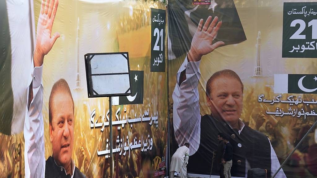 Arbeiter legen letzte Hand an die riesigen Porträts des ehemaligen pakistanischen Premierministers Sharif, die am Ort seiner Begrüßungskundgebung aufgestellt sind. Der ehemalige dreifache Premierminister Sharif ist vor den Neuwahlen aus seinem Exil nach Pakistan zurückgekehrt. Foto: K.M. Chaudary/AP