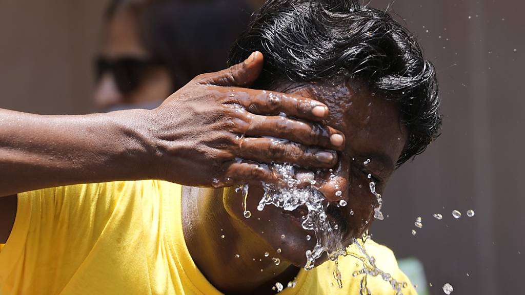 Ein Mann spritzt sich an einem extrem heißen Tag auf einem Marktplatz in Mumbai Wasser ins Gesicht. Indien und Pakistan leiden unter einer frühen Hitzewelle. Indien hat bereits den heißesten März seit Beginn der Wetteraufzeichnungen vor 122 Jahren erlebt. Foto: Rajanish Kakade/AP/dpa