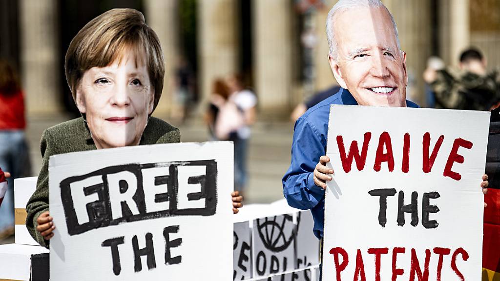 Aktivisten mit Masken, die Bundeskanzlerin Merkel und den US-Präsidenten Biden darstellen, stehen vor dem Brandenburger Tor in Berlin. Die Aktivisten fordern die vorübergehende Aussetzung des Patentschutzes für die Covid-Impfstoffe. Foto: Fabian Sommer/dpa