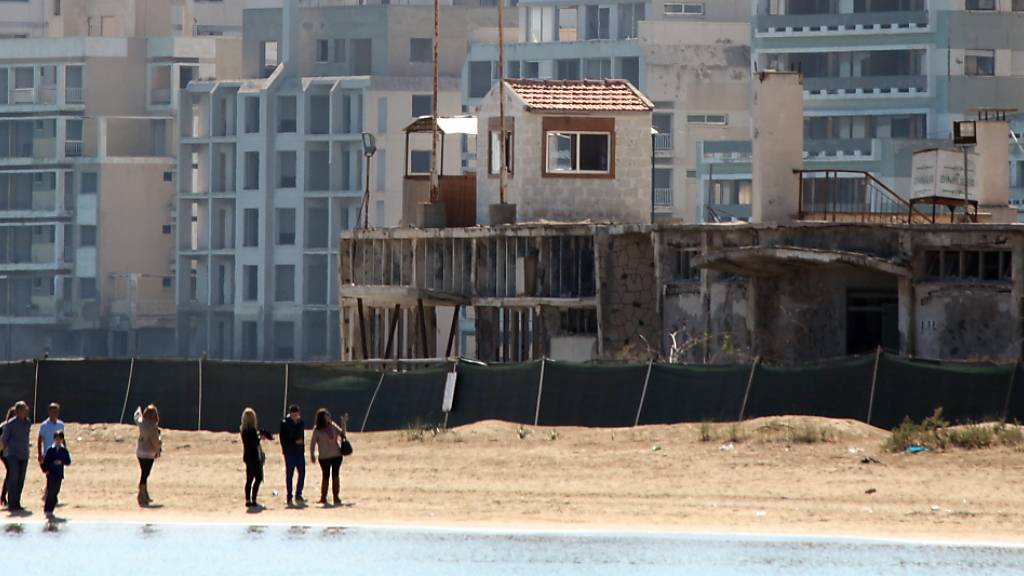 ARCHIV - Menschen spazieren am Strand bei einem militärischen Wachposten, vor verlassenen Hotels in einem vom türkischen Militär genutzten Gebiet im türkisch besetzten Gebiet in der verlassenen Küstenstadt Varosha. Foto: Katia Christodoulou/EPA/dpa