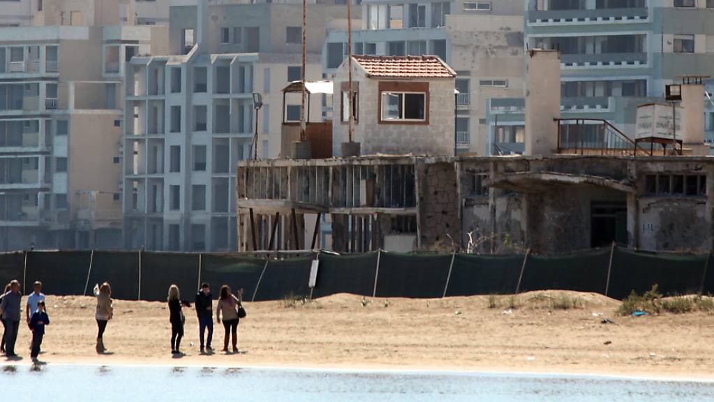ARCHIV - Menschen spazieren am Strand bei einem militärischen Wachposten, vor verlassenen Hotels in einem vom türkischen Militär genutzten Gebiet im türkisch besetzten Gebiet in der verlassenen Küstenstadt Varosha. Foto: Katia Christodoulou/EPA/dpa