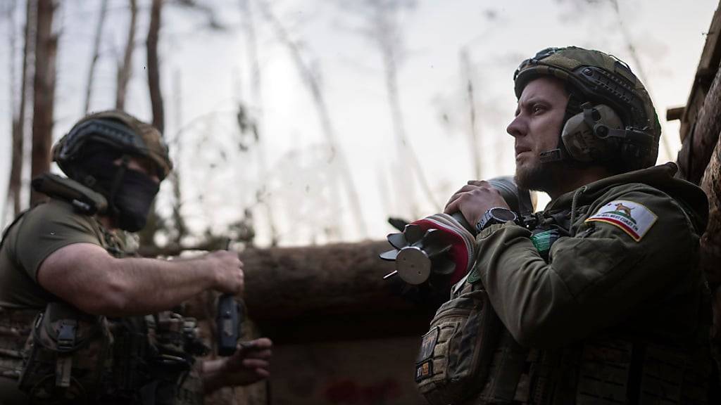 Ein ukrainischer Soldat der Asow-Brigade, bekannt unter dem Rufnamen Chaos, rechts, trägt eine Mörsergranate, während er auf einen Feuerbefehl wartet. Foto: Alex Babenko/AP