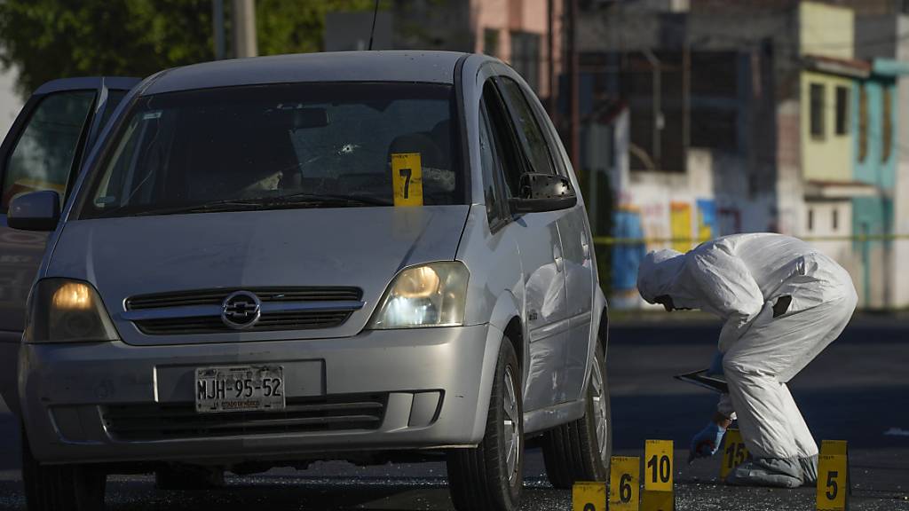 ARCHIV - Ein Polizeiermittler sammelt Beweise an der Stelle, an der ein Polizist in Celaya, Mexiko erschossen wurde. Foto: Fernando Llano/AP/dpa