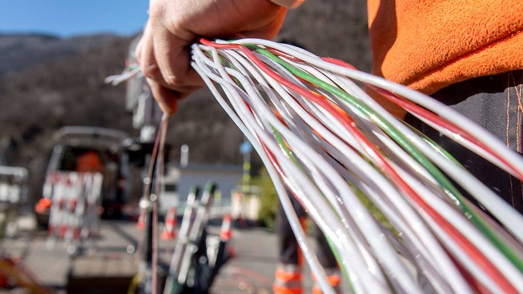 Ein Arbeiter montiert Glasfaserkabel der Swisscom. Die Comcom stützt sich bei der Preisberechnung für die Mitbenützung des Swisscom-Netzes neu auf die Kosten für Glasfaserleitungen. (Archiv)