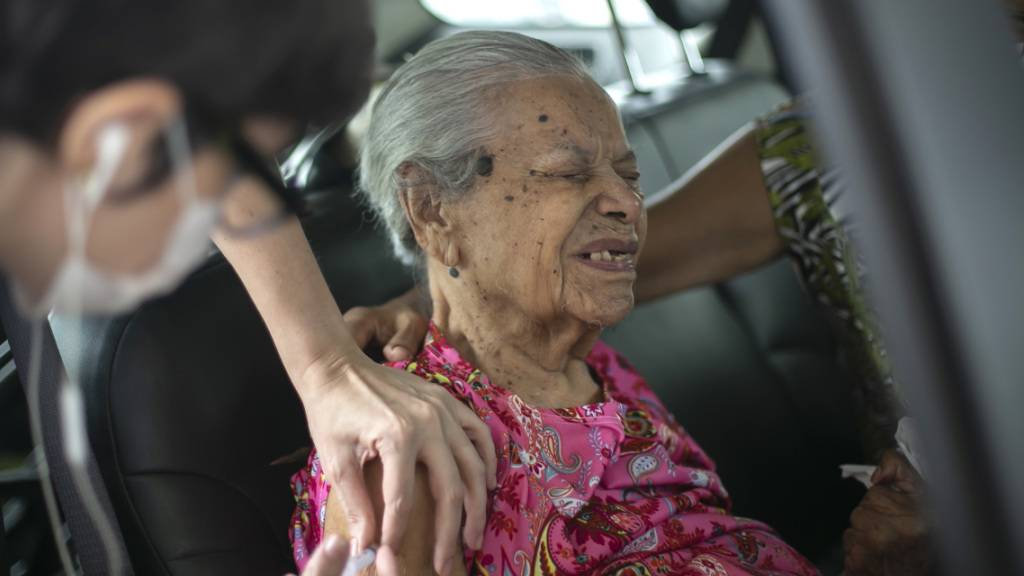 Maria de Lourdes (101) verzerrt das Gesicht, während sie eine Dosis des chinesischen Impfstoffs Sinovac Biotech COVID-19 an einer Drive-Thru-Impfstelle im Sambadrome erhält. Foto: Bruna Prado/AP/dpa