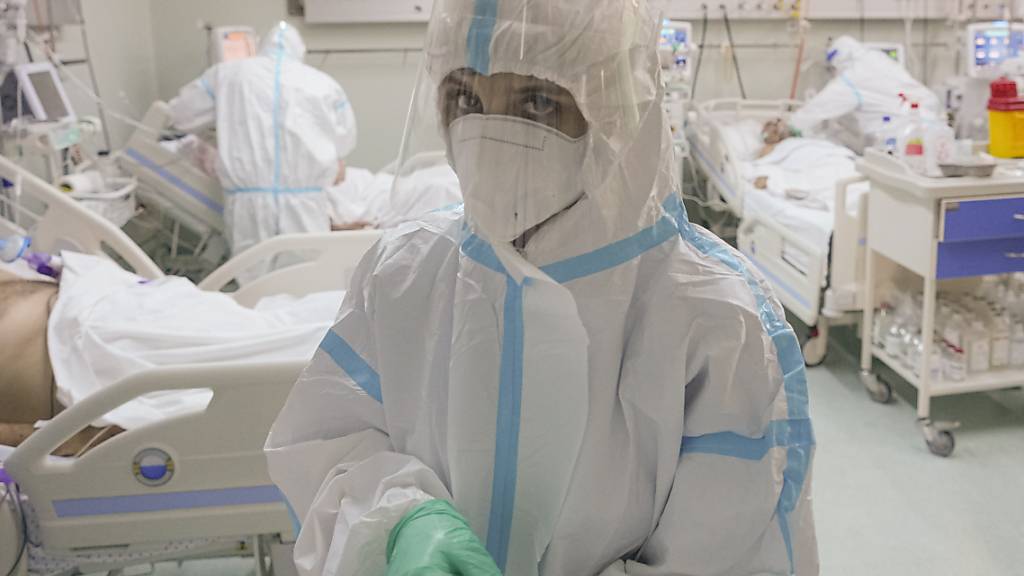 Eine medizinische Mitarbeiterin richtet ihre Handschuhe auf der Corona-Intensivstation. Foto: Vadim Ghirda/AP/dpa