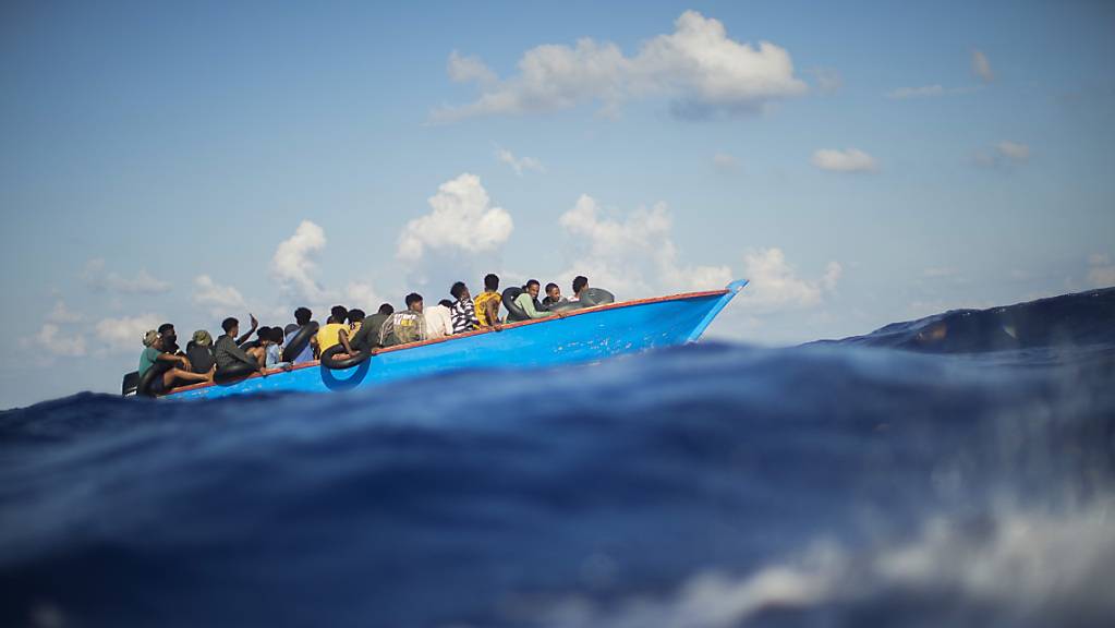 Migranten sitzen in einem Holzboot südlich der italienischen Insel Lampedusa auf dem Mittelmeer. 