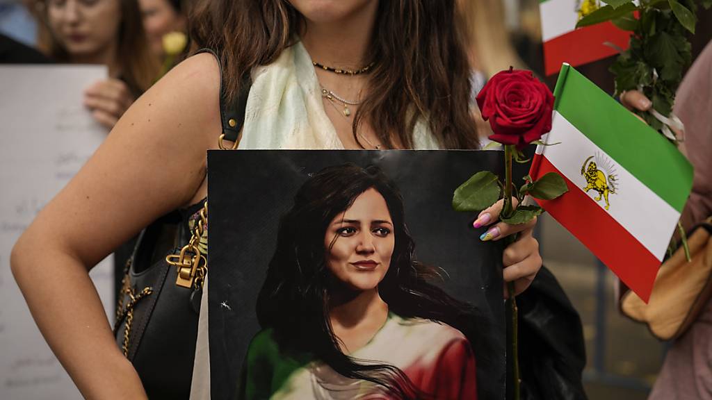 Wegen eines solchen Bildes muss die Schweizer Botschafterin im Aussenministerium in Teheran vorsprechen: Eine Manifestantin hält in Bukarest ein Bild der umgekommenen Kurdin und die alte Flagge des Irans. (Archivbild)