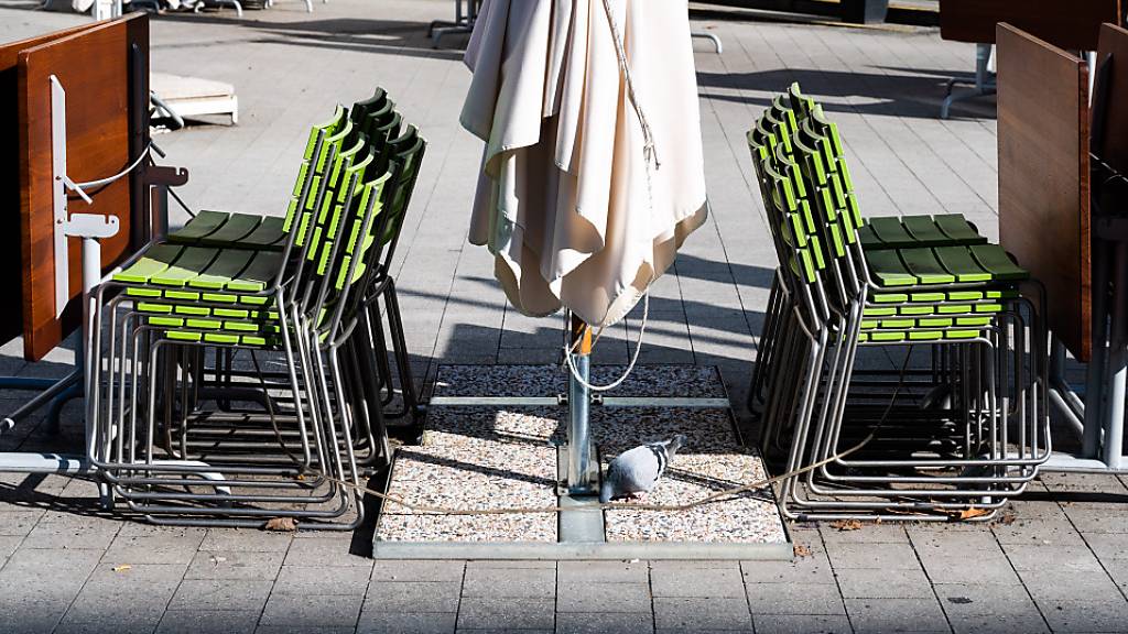 Gestapelte Stühle und zusammengeklappte Tische stehen in der Außengastronomie eines geschlossenen Restaurants in der Hannoveraner Innenstadt.