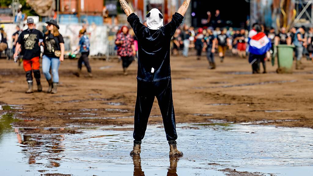 Ein Mann in einem Pandakostüm feiert beim Wacken Open Air in einer Schlammpfütze auf dem Festivalgelände. Foto: Axel Heimken/dpa