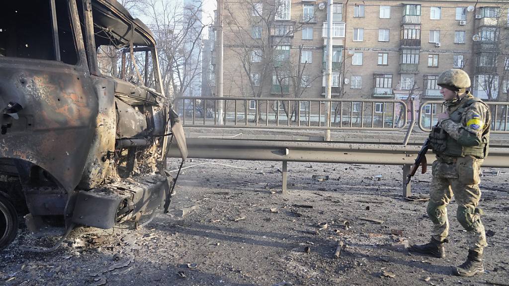 Ein ukrainischer Soldat geht an den Trümmern eines brennenden Militärlastwagens vorbei. Foto: Efrem Lukatsky/AP/dpa
