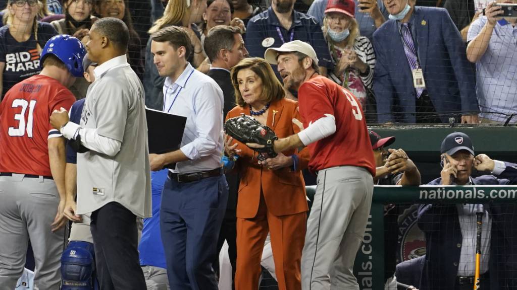 Präsident Joe Biden (rechts) telefoniert, während die Sprecherin des Repräsentantenhauses, Nancy Pelosi (Mitte) das Baseballspiel des Kongresses verfolgt.
