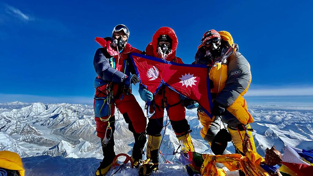ILLUSTRATION - Nima Lhamu Sherpa (M) steht mit ihren Brüdern auf dem Gipfel des Mount Everest. Foto: Grace Best/Nima Lhamu Sherpa/dpa - ACHTUNG: Nur zur redaktionellen Verwendung im Zusammenhang mit der Berichterstattung über die Geschwister auf dem Mount Everest und nur mit vollständiger Nennung des vorstehenden Credits