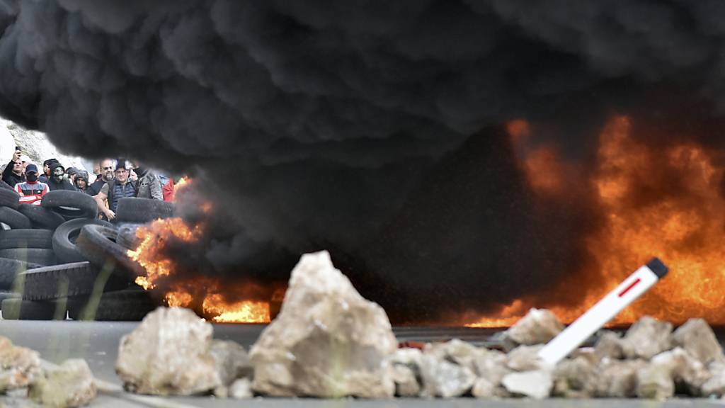 Rauch steigt von brennenden Reifen auf, die Demonstranten bei einer der Blockaden in Brand gesetzt haben. Foto: Risto Bozovic/AP/dpa