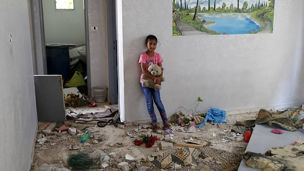 Die 10-jährige Rahaf Abu Fares, die vier Familienmitglieder verlor, als ihr Haus während des elftägigen Gefechts zwischen Israel und der Hamas im Mai von israelischer Artillerie bombardiert wurde, trägt einen Teddybär inmitten der Trümmer ihres Hauses im Beduinendorf Umm Al-Nasr. Foto: Adel Hana/AP/dpa