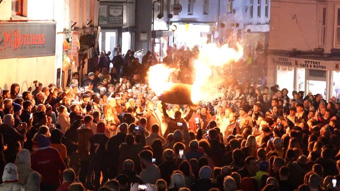 Engländer tragen brennendes Teerfass durch Stadt