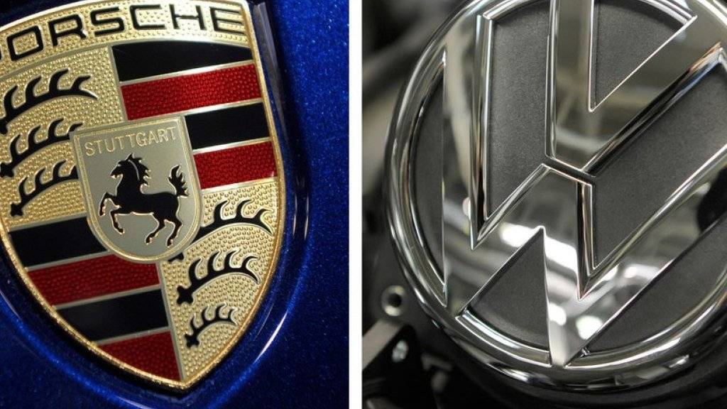 Porsche-Logo auf der Motorhaube eines Cayenne neben einem VW-Logo. (Symbolbild)